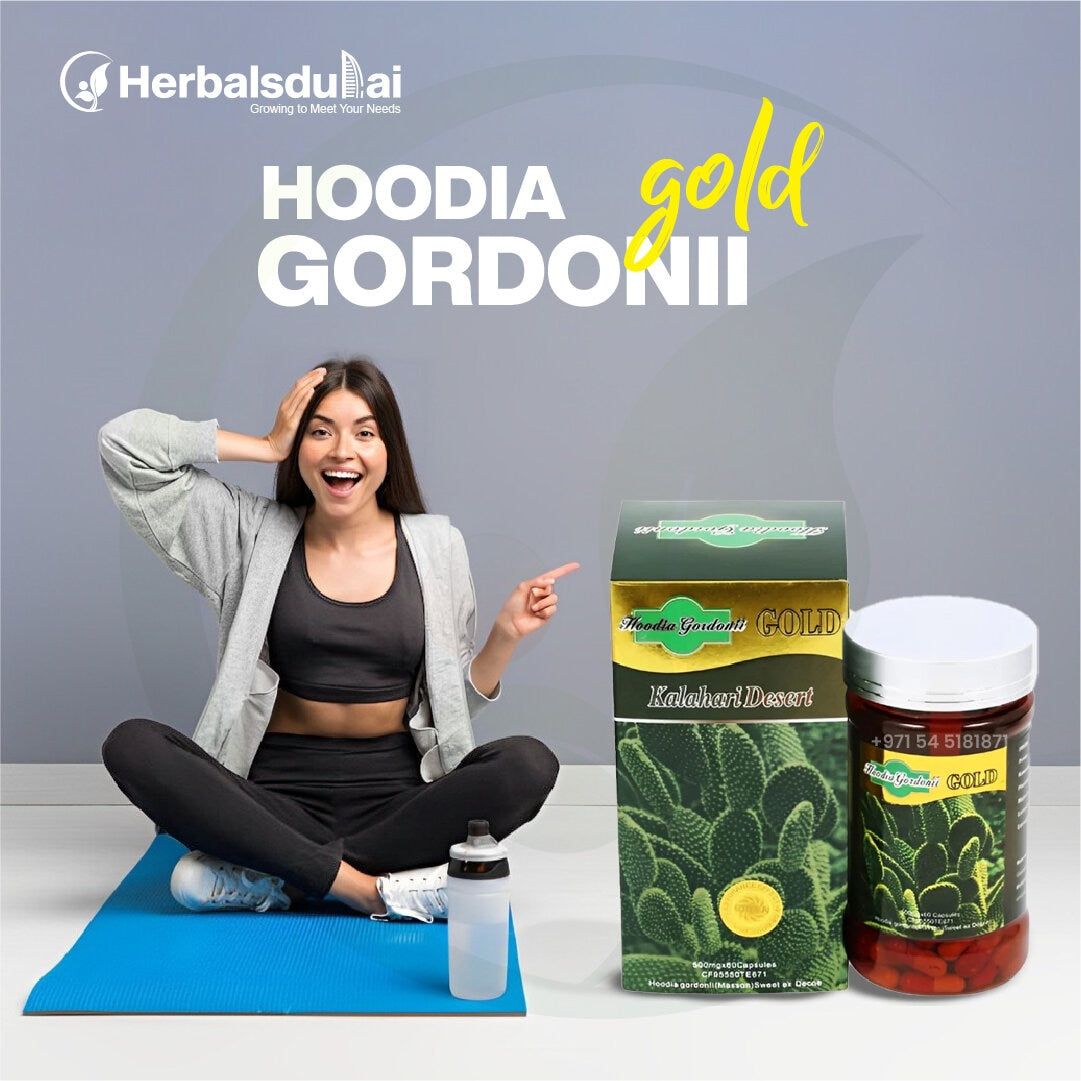 Woman sitting on a yoga mat with a smile, pointing to Hoodia Gordonii Gold products from Herbals Dubai, including a box and a bottle, with a water bottle nearby.