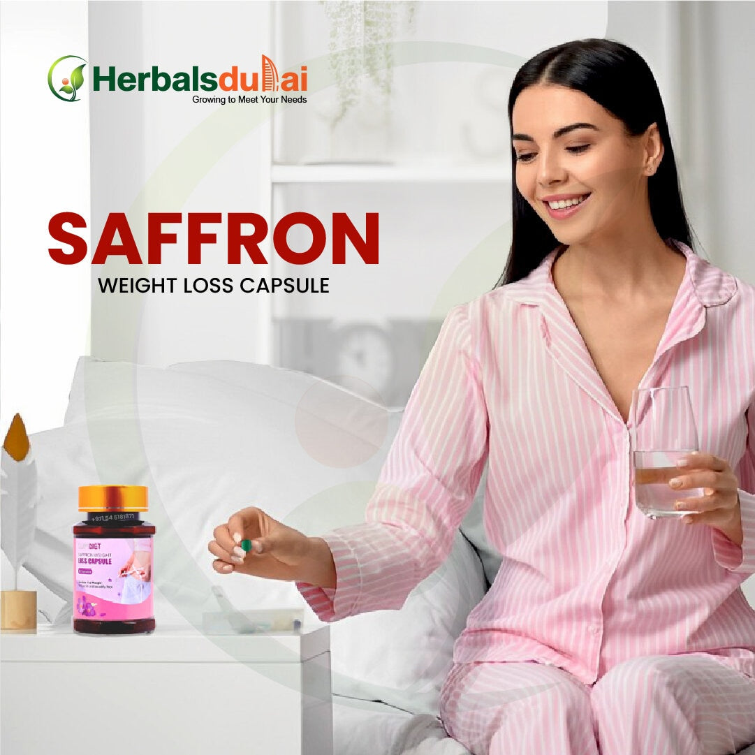 A woman in pink pajamas sits on her bed holding a glass of water and taking a saffron weight loss capsule, with a bottle of the capsules visible on her bedside table. The product is by Herbals Dubai.