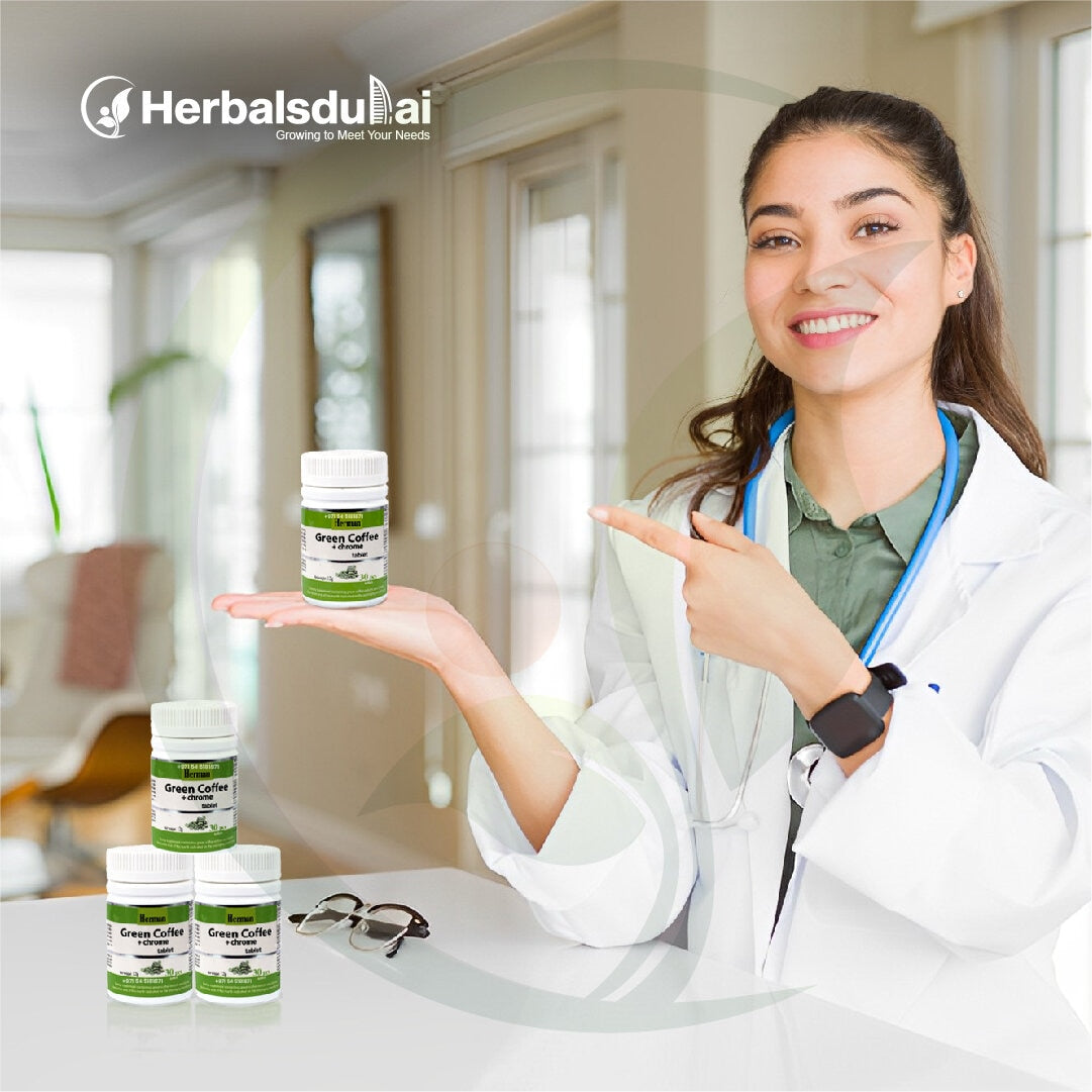 A smiling doctor in a white coat holding and pointing at a bottle of Herbasldulai green coffee supplements, with more bottles arranged on a table nearby in a home setting.